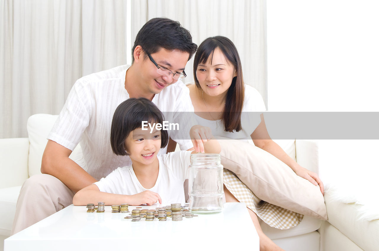 Smiling family with coins on table at home