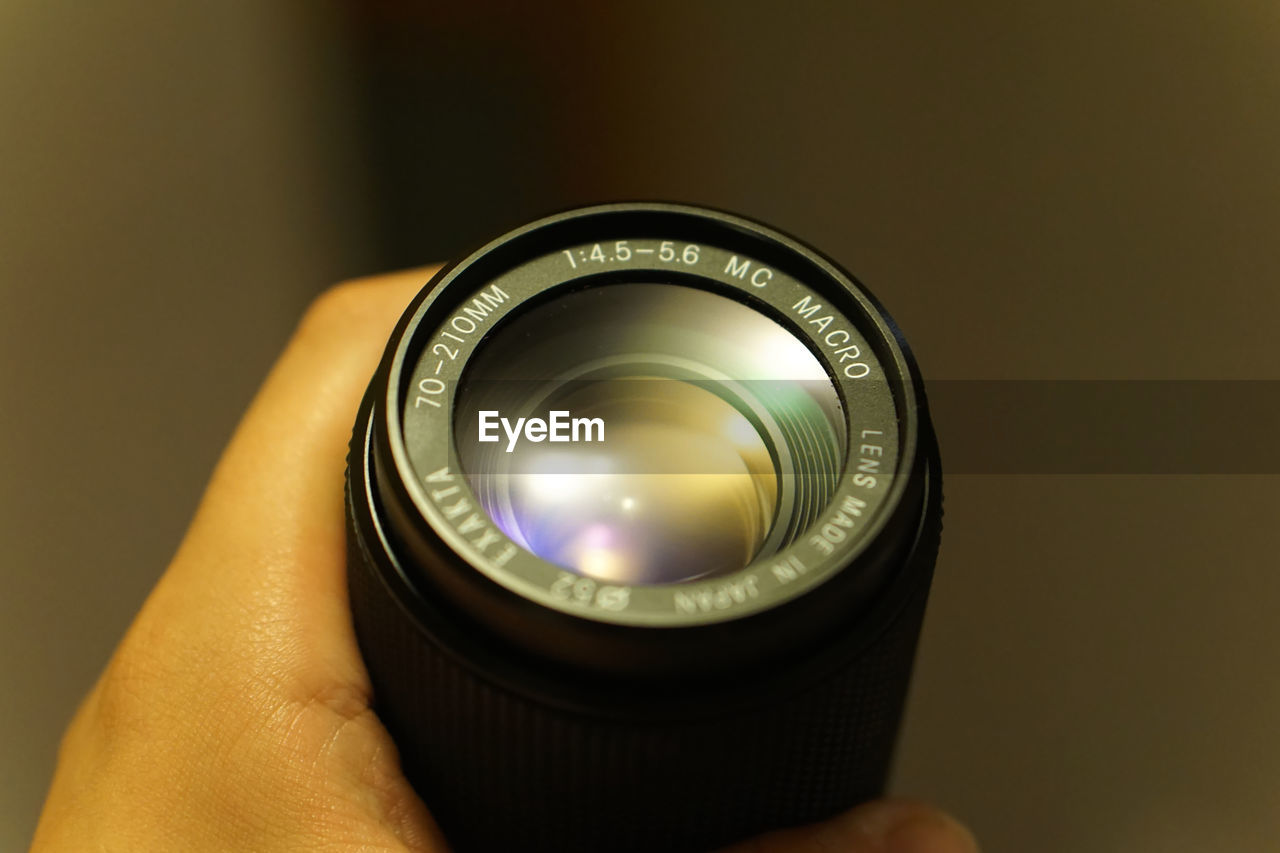 Cropped image of hand holding digital camera lens