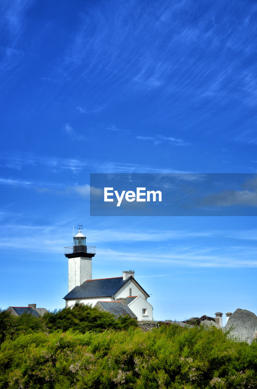 LIGHTHOUSE BY BUILDING AGAINST BLUE SKY