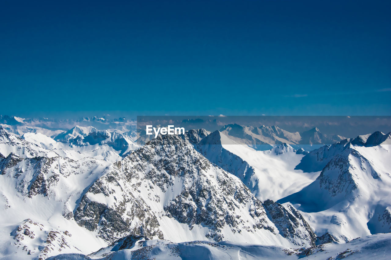 Scenic view of snowcapped mountains against blue sky