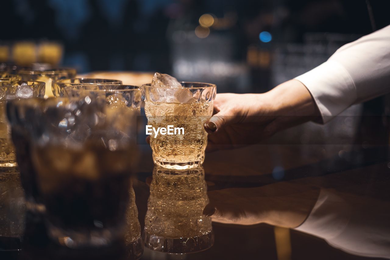 Cropped hand holding drinking glass on table