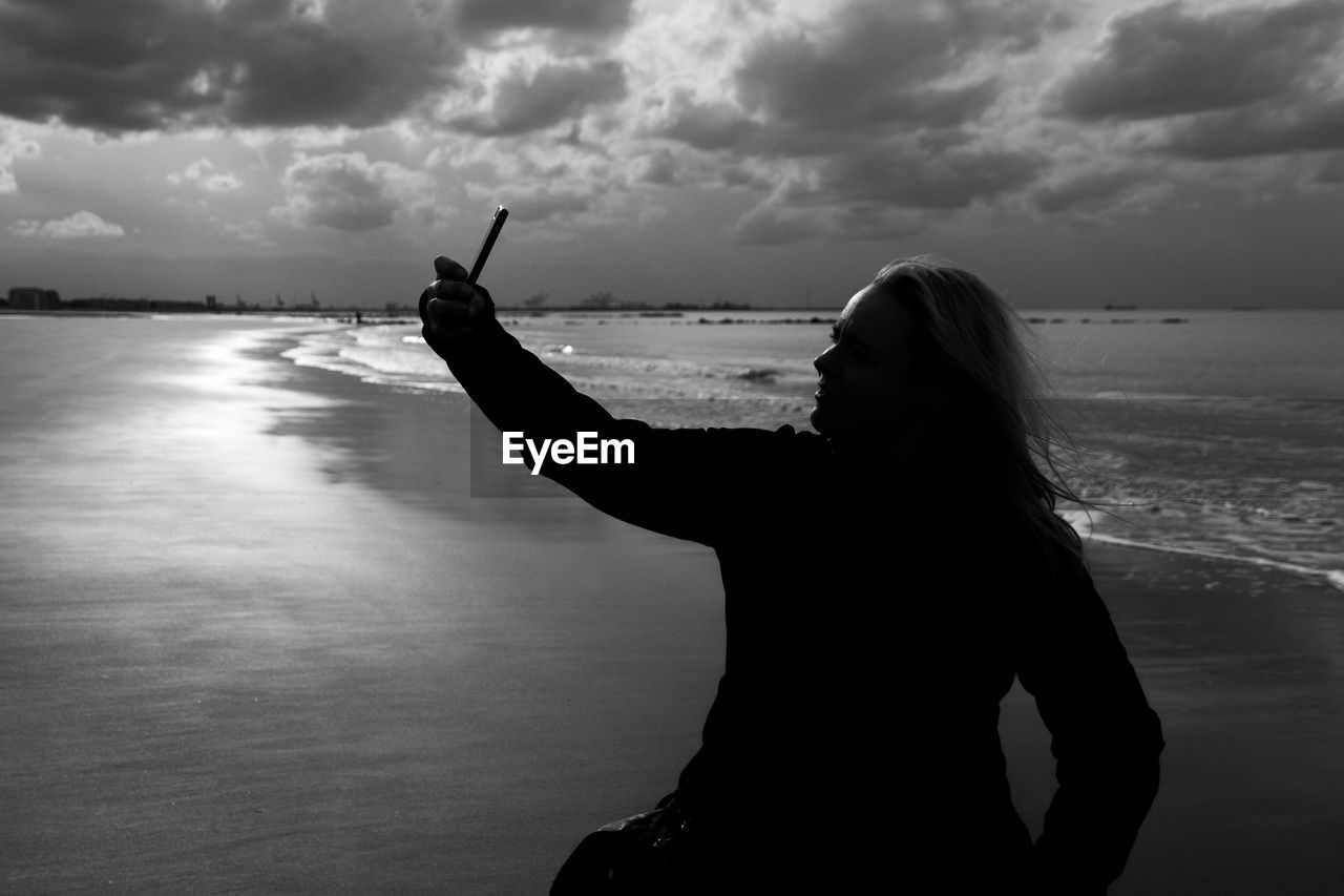 Woman taking selfie through mobile phone at beach