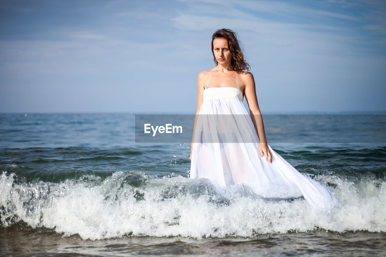 YOUNG WOMAN ON BEACH AGAINST SKY