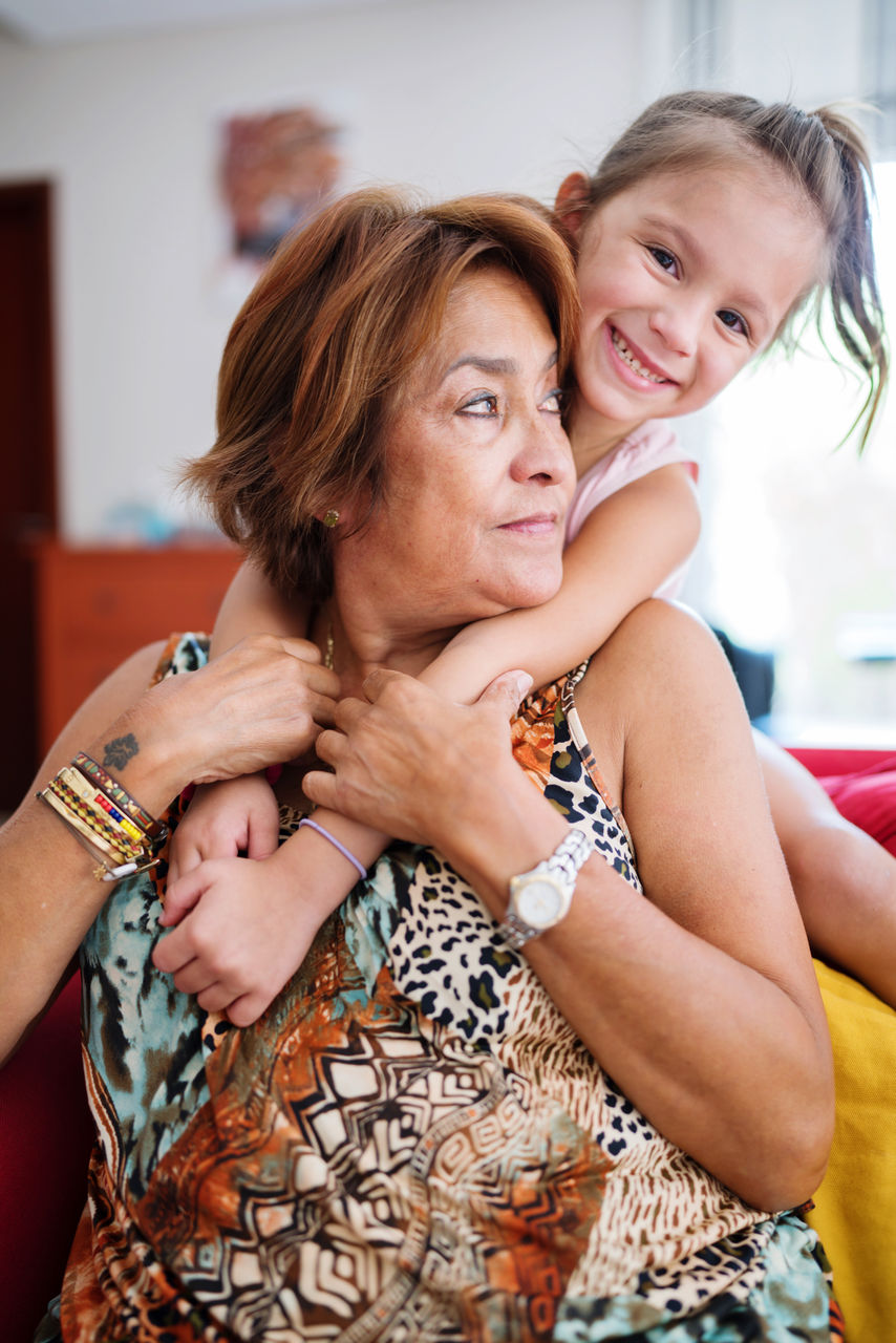 Grandmother hugging on the sofa with her granddaughter 