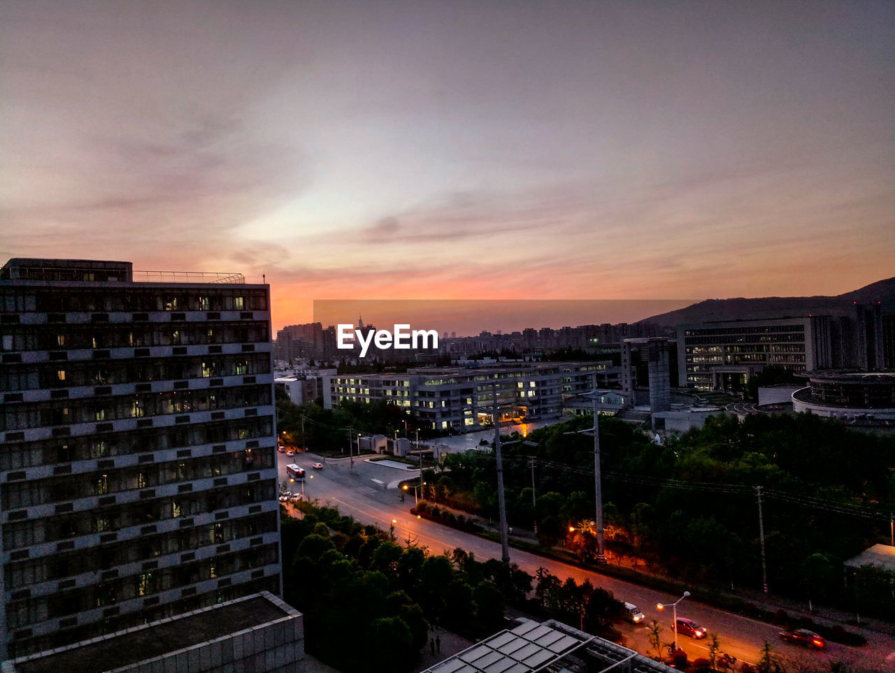 HIGH ANGLE VIEW OF ILLUMINATED CITY AT SUNSET