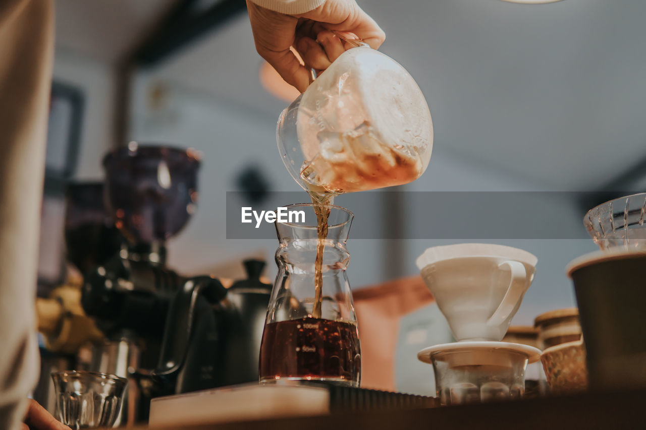 Close-up of hand pouring coffee in cup