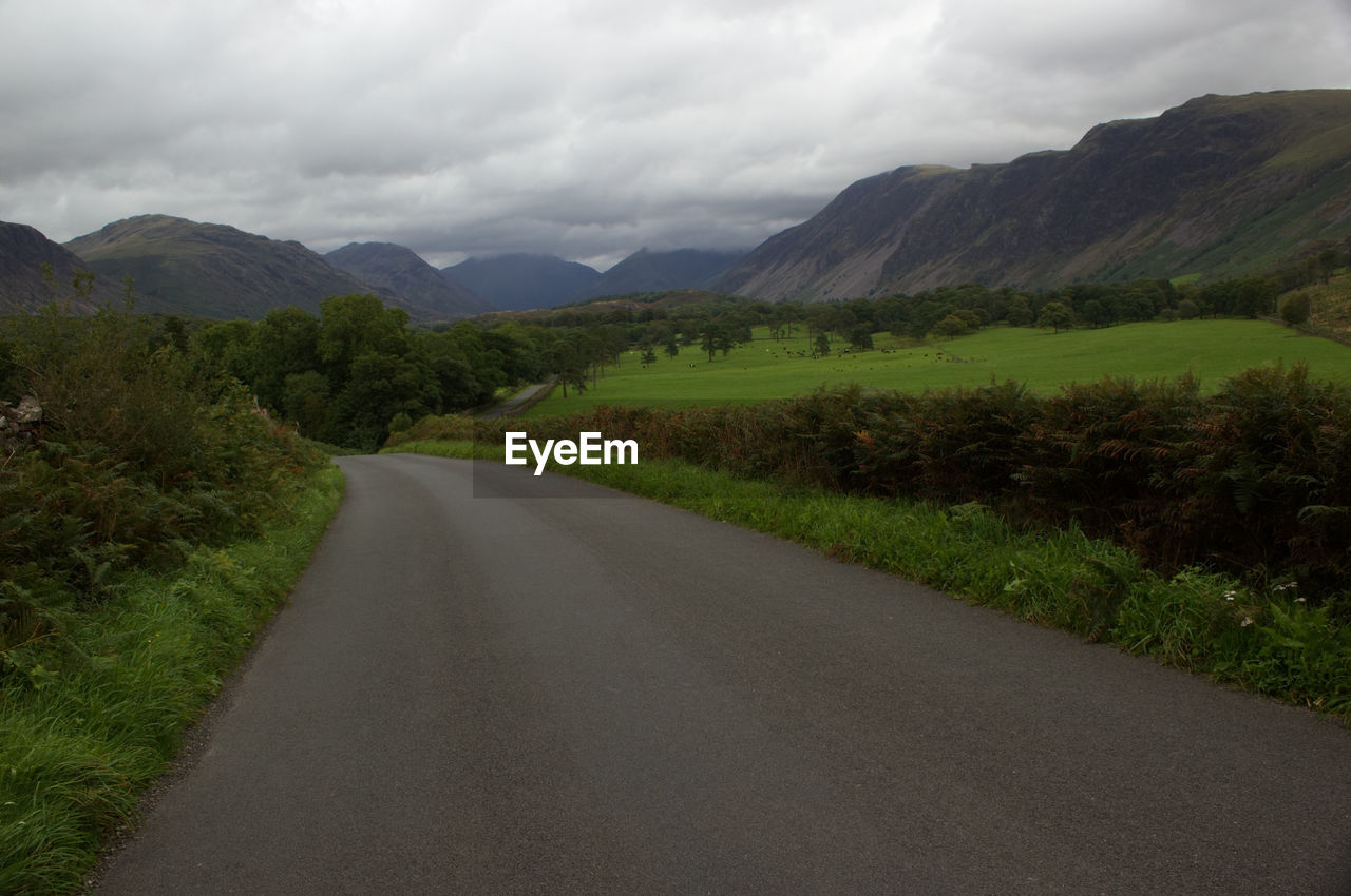 Road leading towards mountains against sky