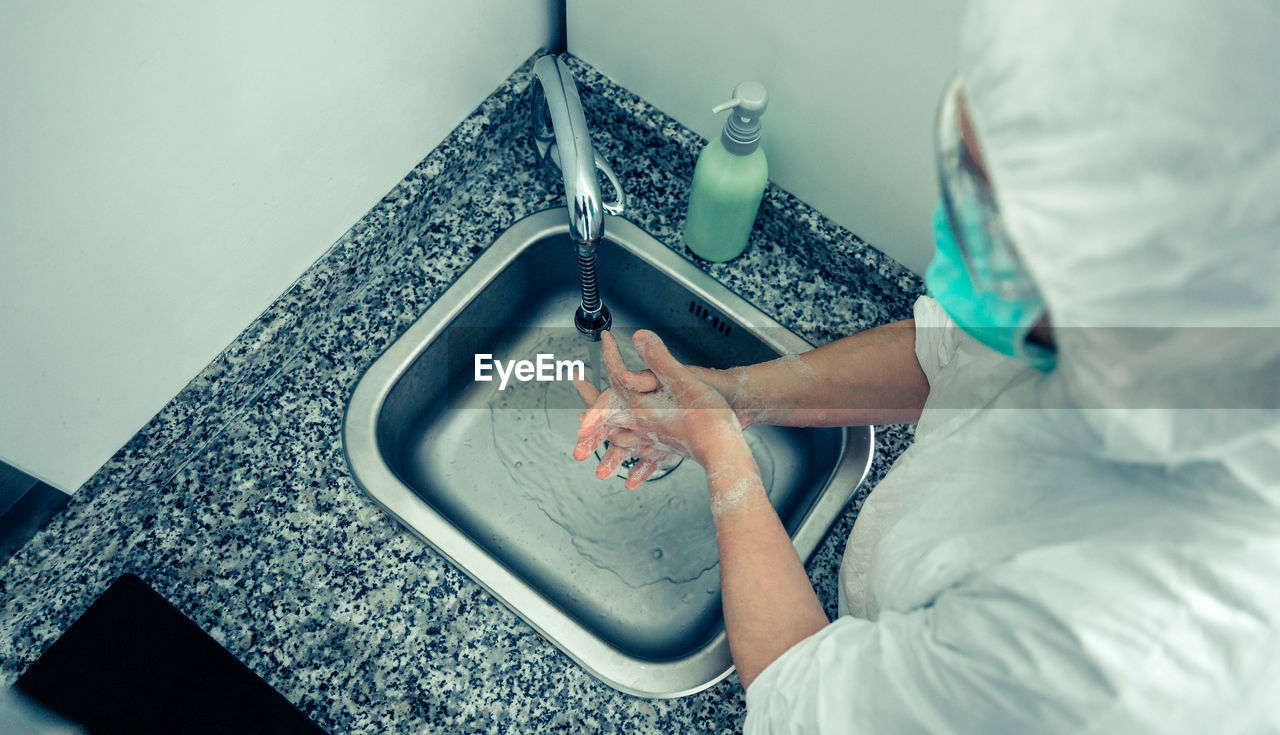 High angle view of doctor washing hands in bathroom sink