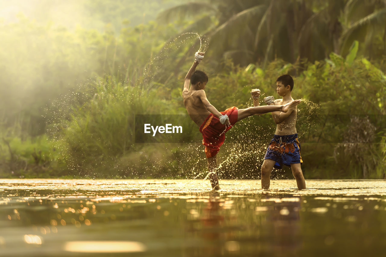 Full length of shirtless boys playing in water