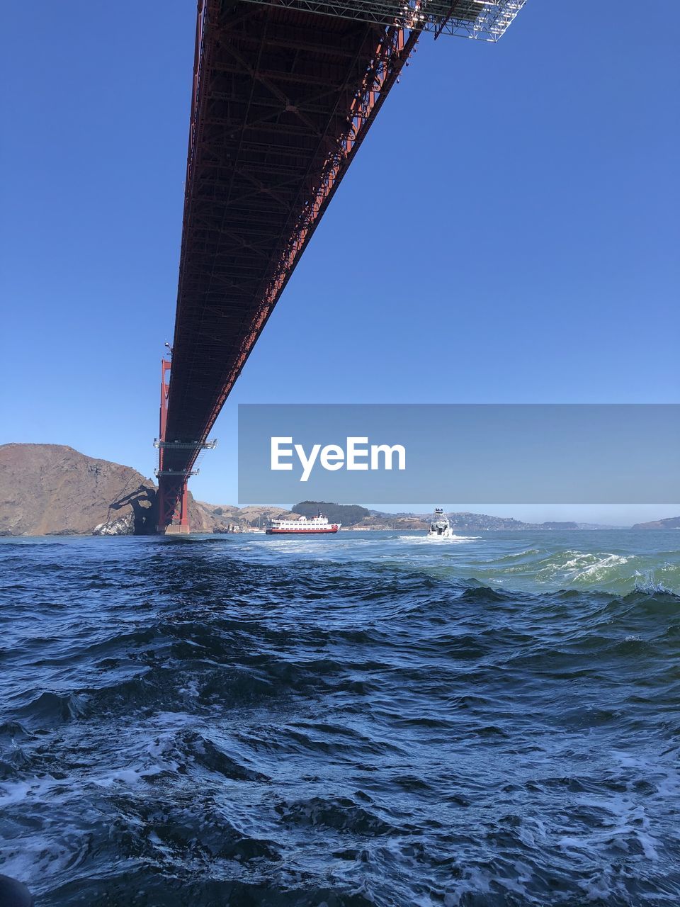 Bridge over sea against clear blue sky