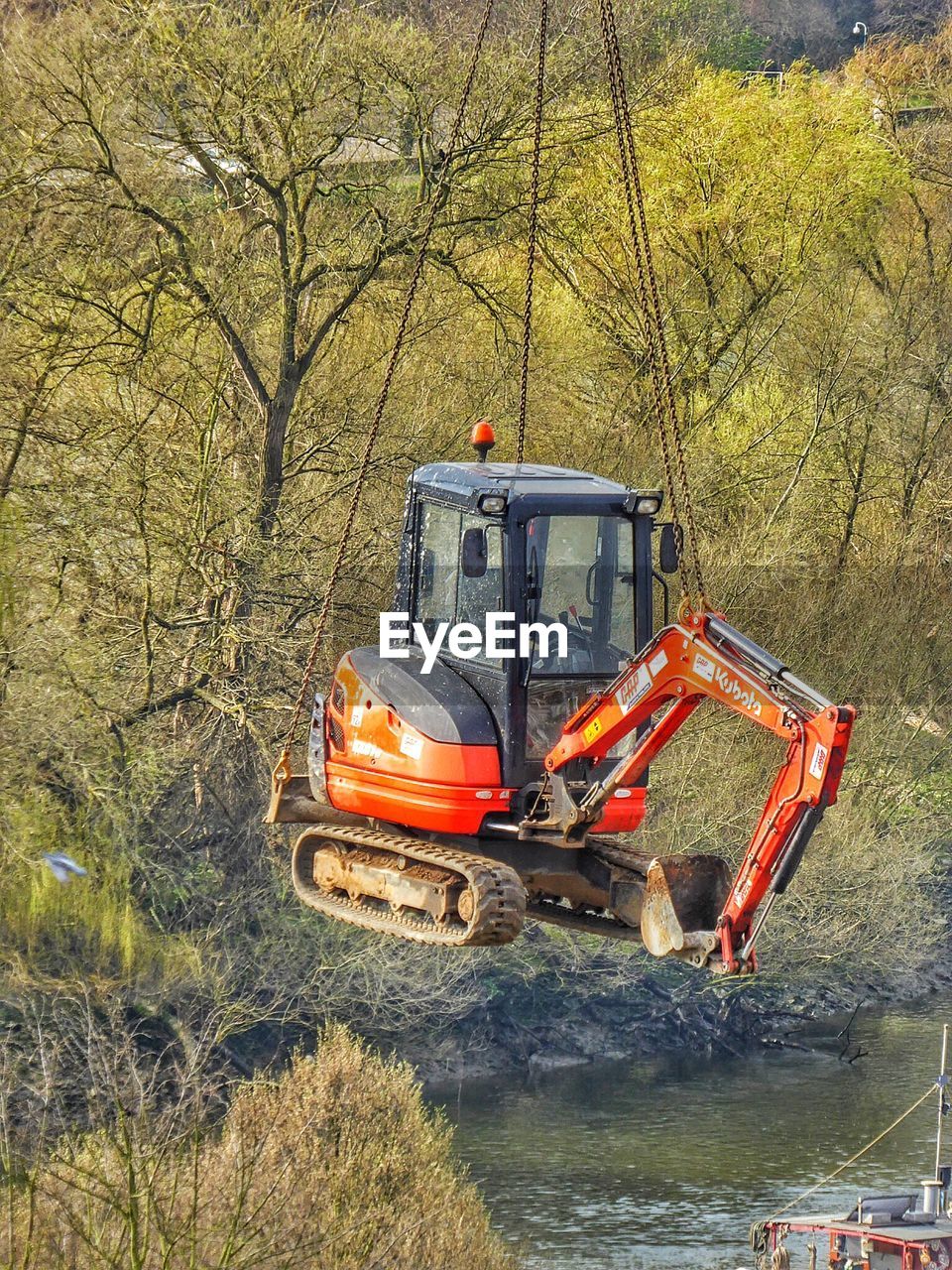 Excavator hanging on chain in forest