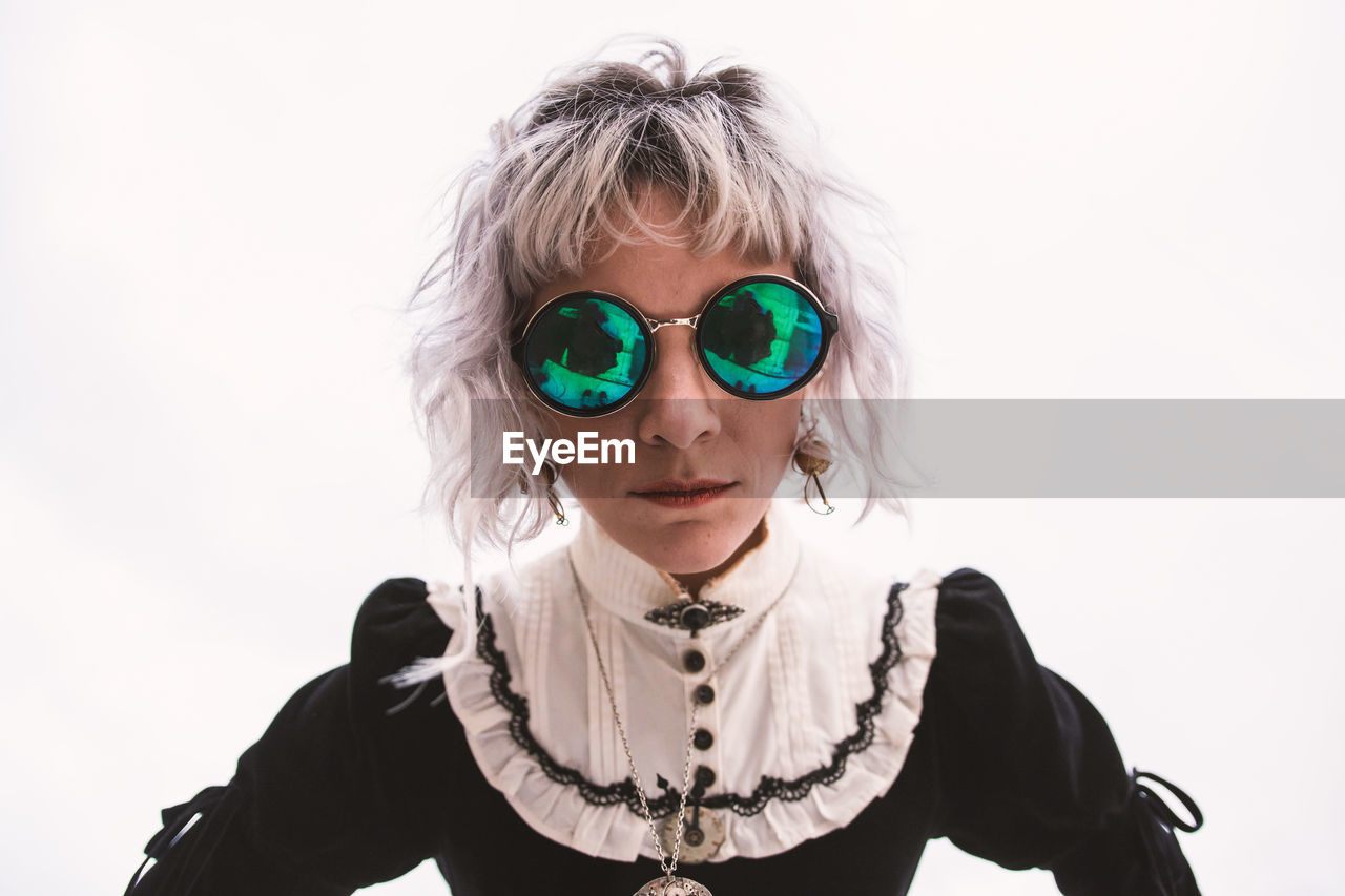 Portrait of woman wearing sunglasses against white background