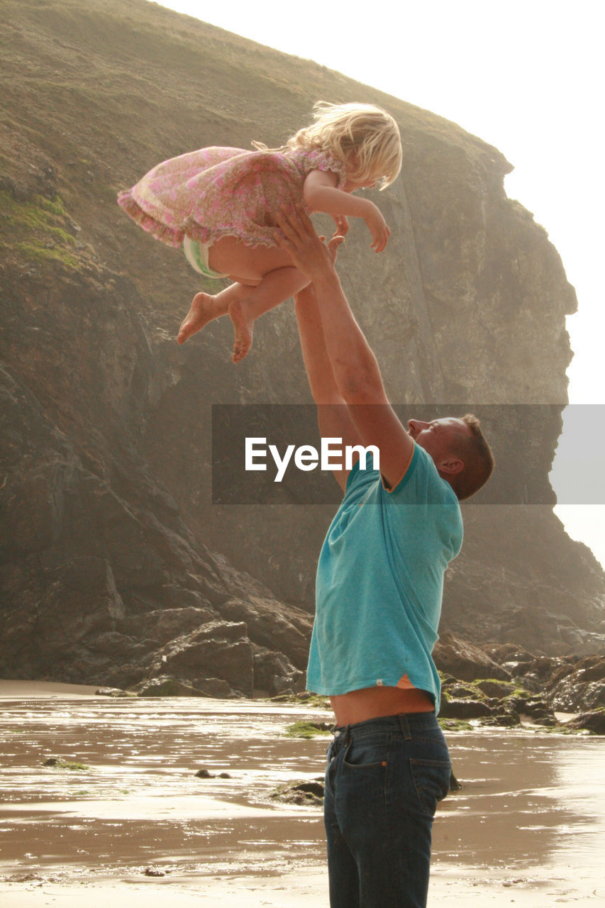 Full length of man playing with daughter on the beach