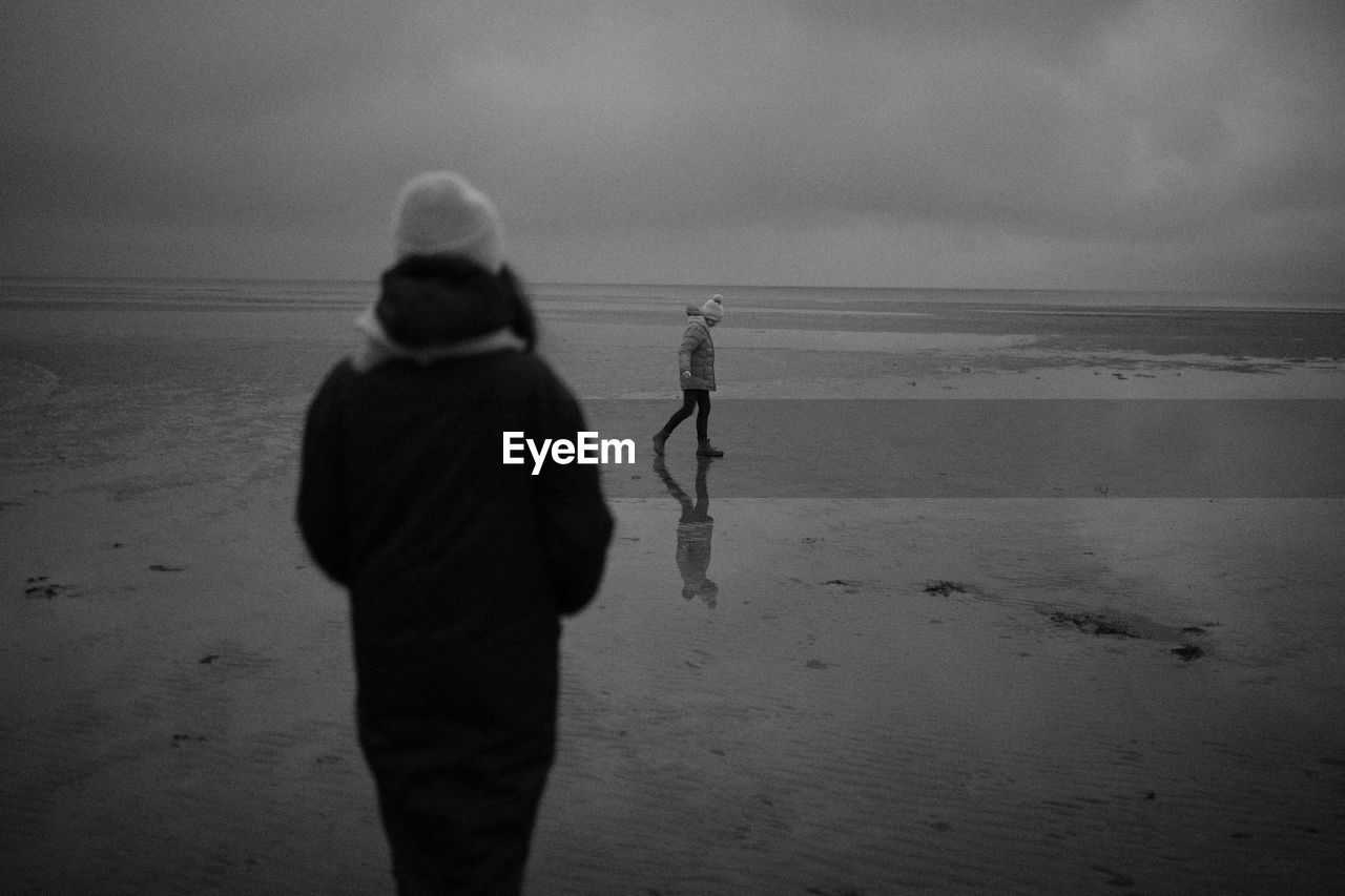 Men walking on beach against sky