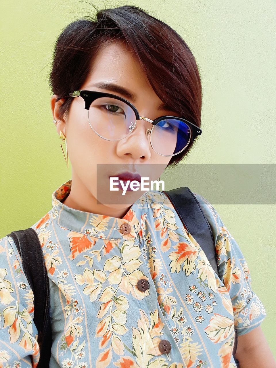 Portrait of woman wearing eyeglasses against green background