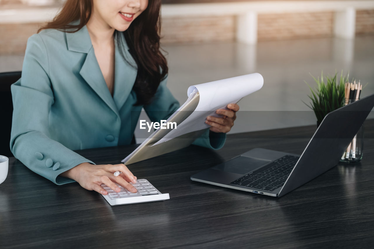 midsection of young woman using digital tablet on table