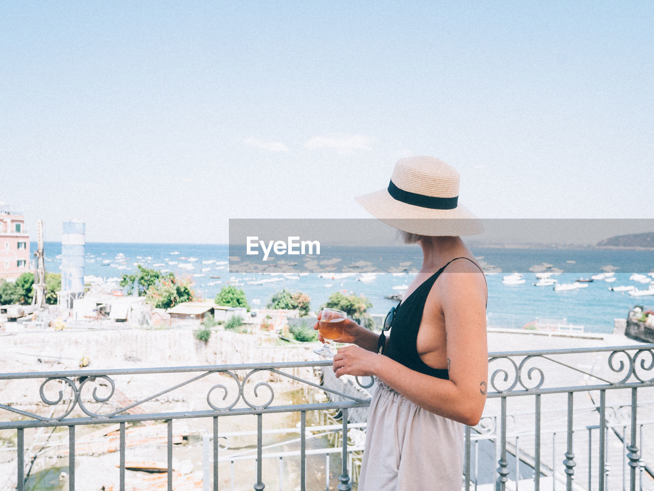 MAN LOOKING AT SEA AGAINST CITYSCAPE