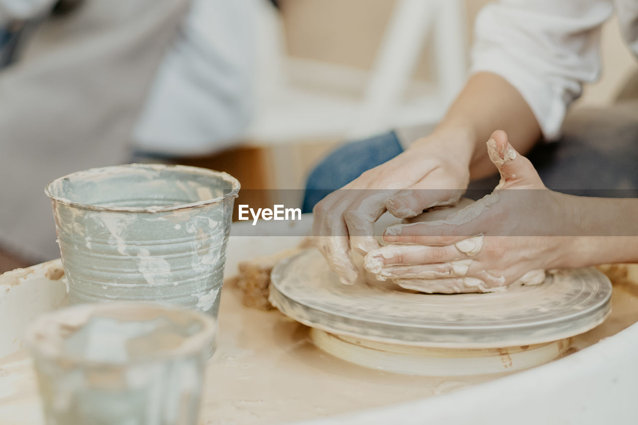 Modeling on a potter's wheel. hands are molded from clay. working atmosphere in the workshop. 