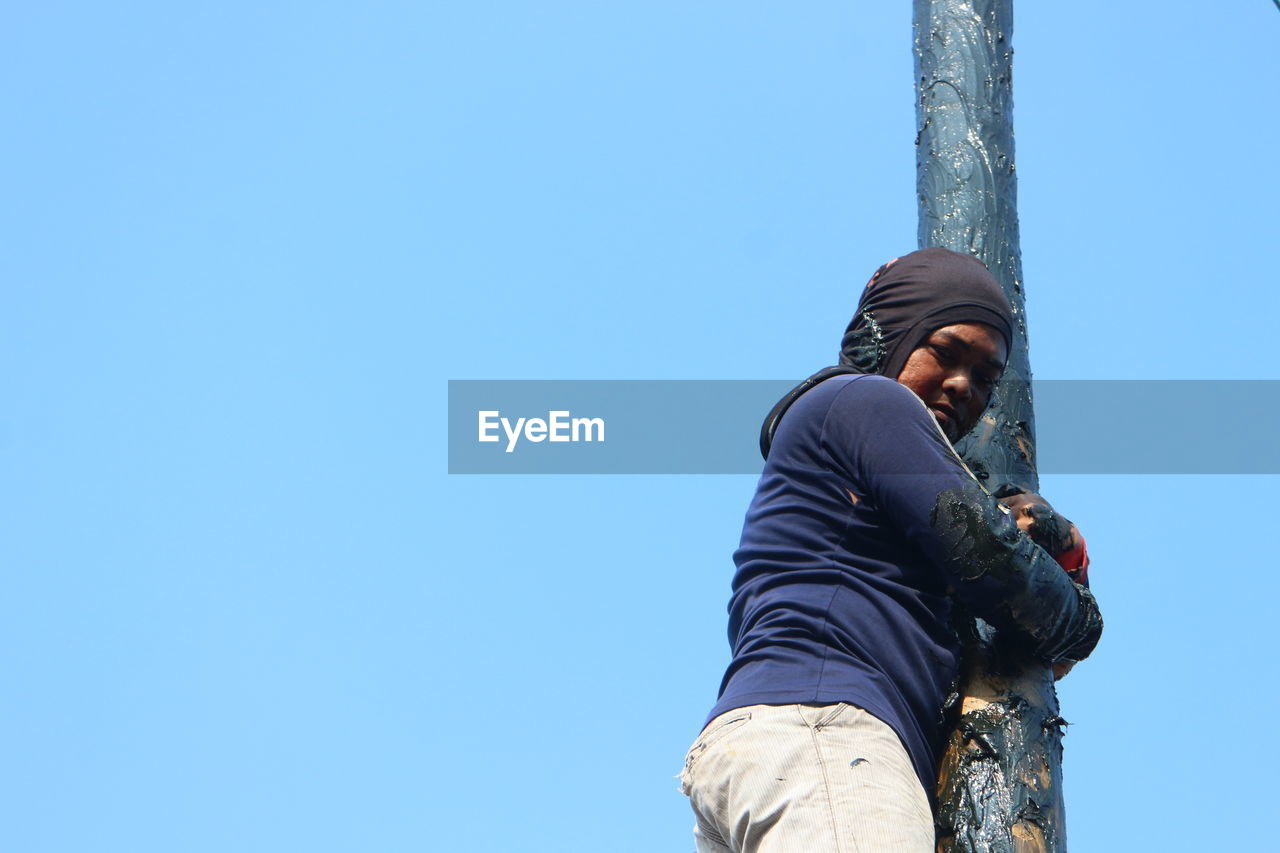 LOW ANGLE VIEW OF MAN STANDING AGAINST SKY