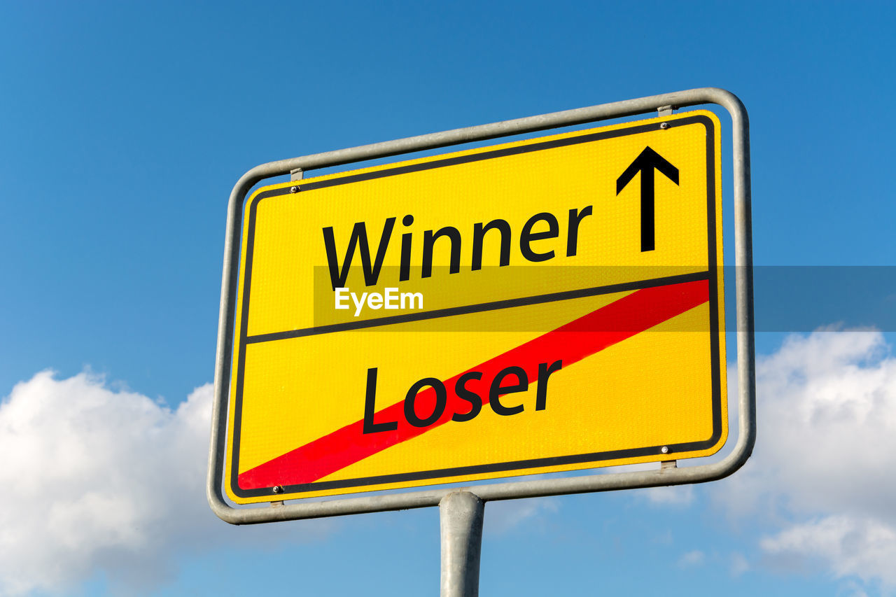 Low angle view of road sign against blue sky