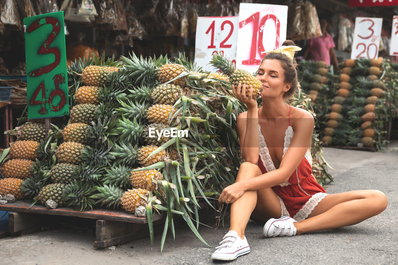 portrait of young woman with pineapple for sale
