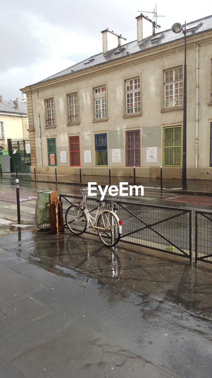 BICYCLES ON STREET BY BUILDINGS AGAINST SKY