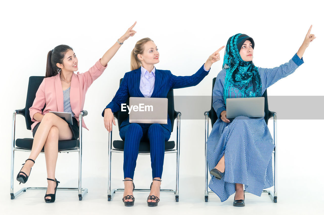 WOMEN SITTING ON WALL WITH PEOPLE