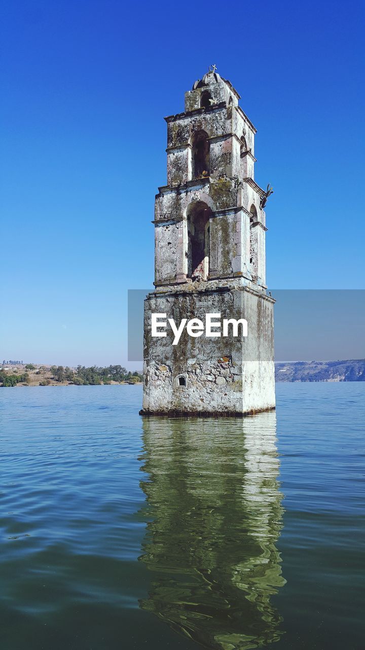 OLD TOWER OF BUILDING BY SEA AGAINST SKY