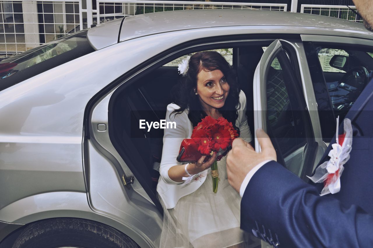 WOMAN HOLDING UMBRELLA WHILE STANDING BY CAR