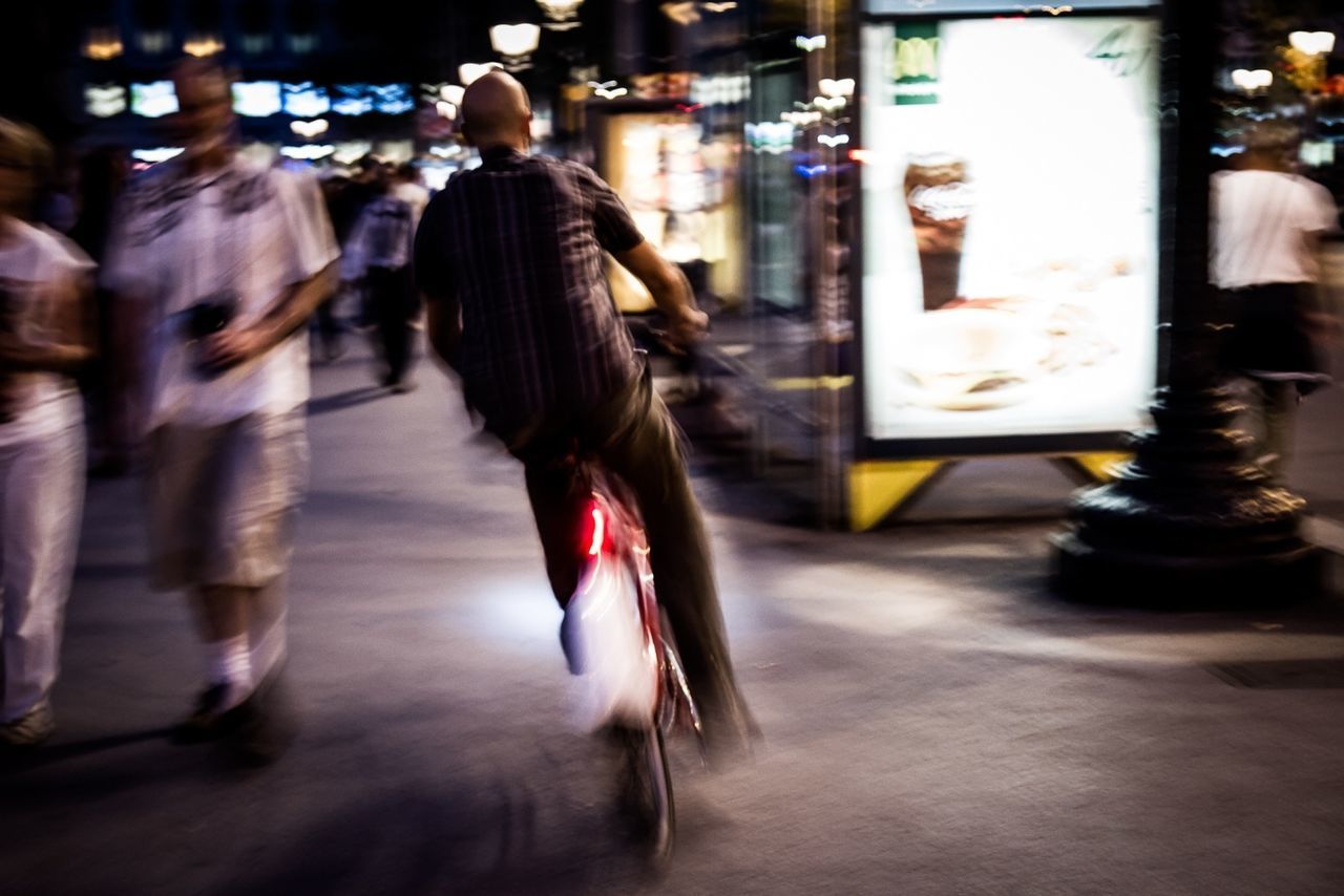 Rare view of man riding bicycle in city at night