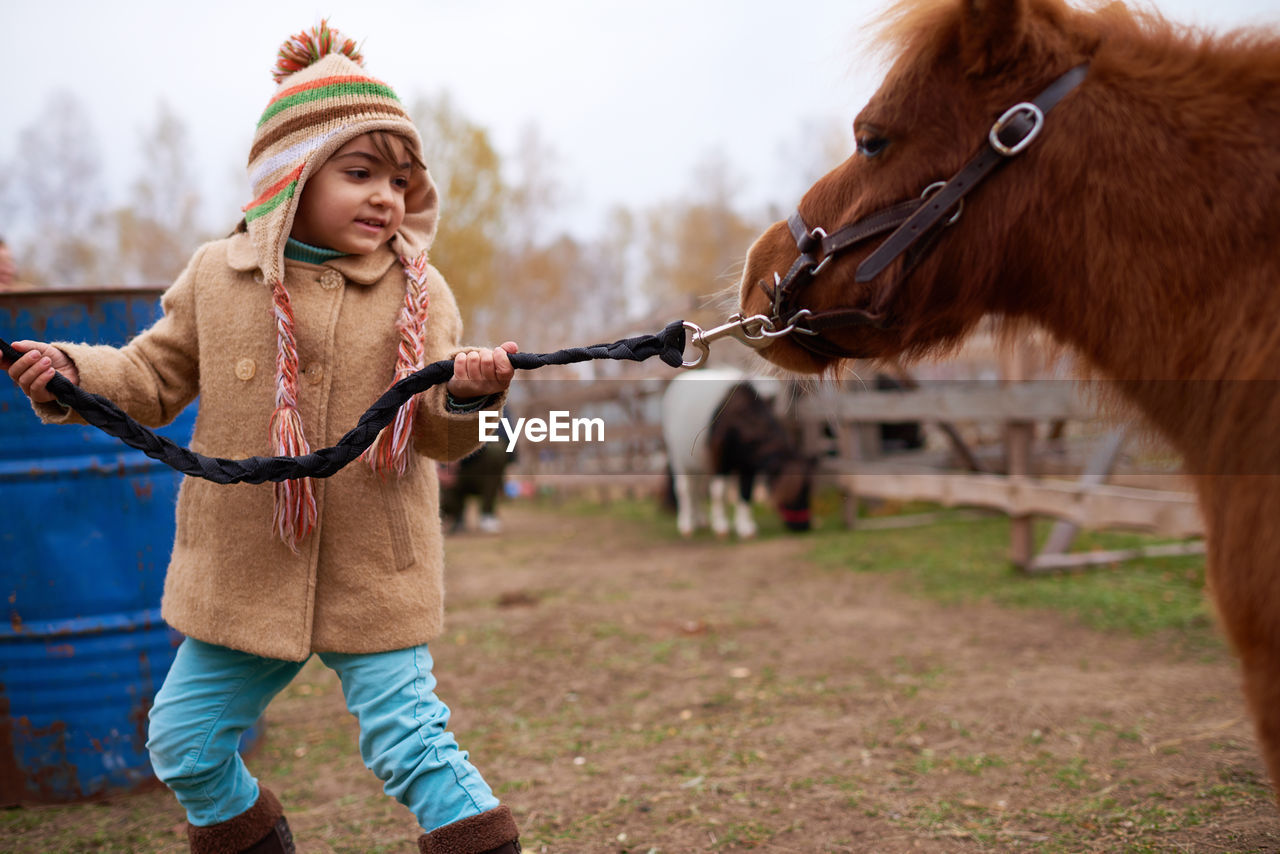 Caucasian girl leading pony by bridle