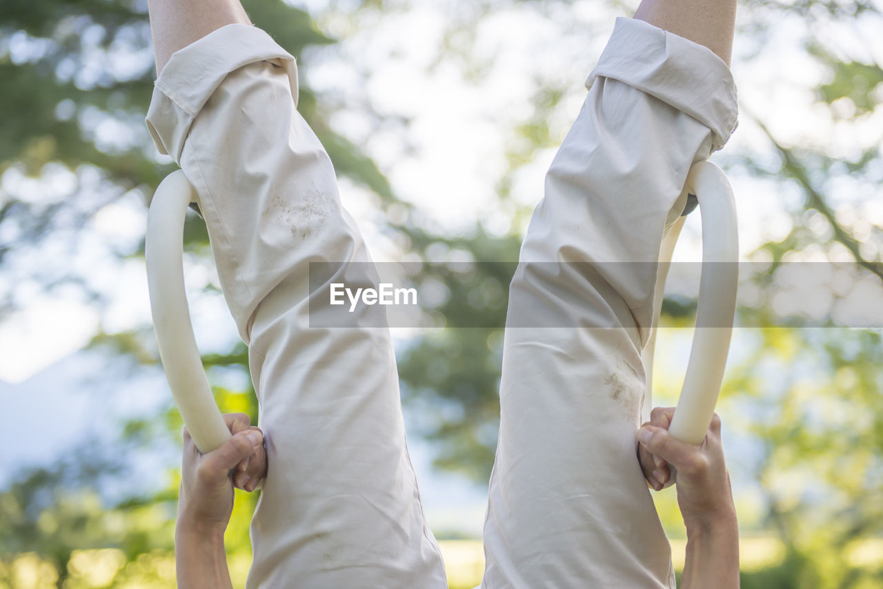 Midsection of woman hanging upside down on gymnastic rings