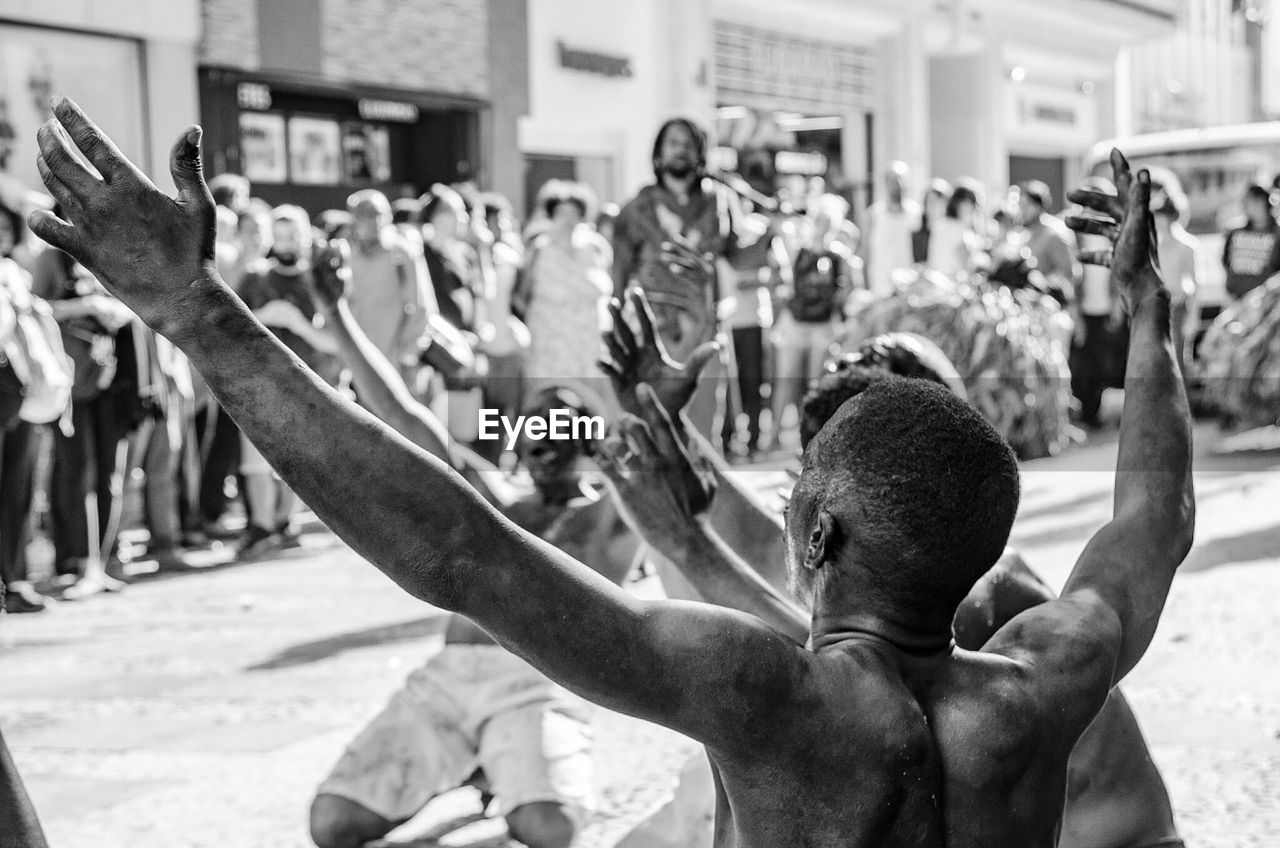 Rear view of people with arms raised on street