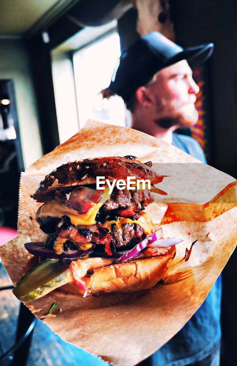 Close-up of hamburger with man standing in background