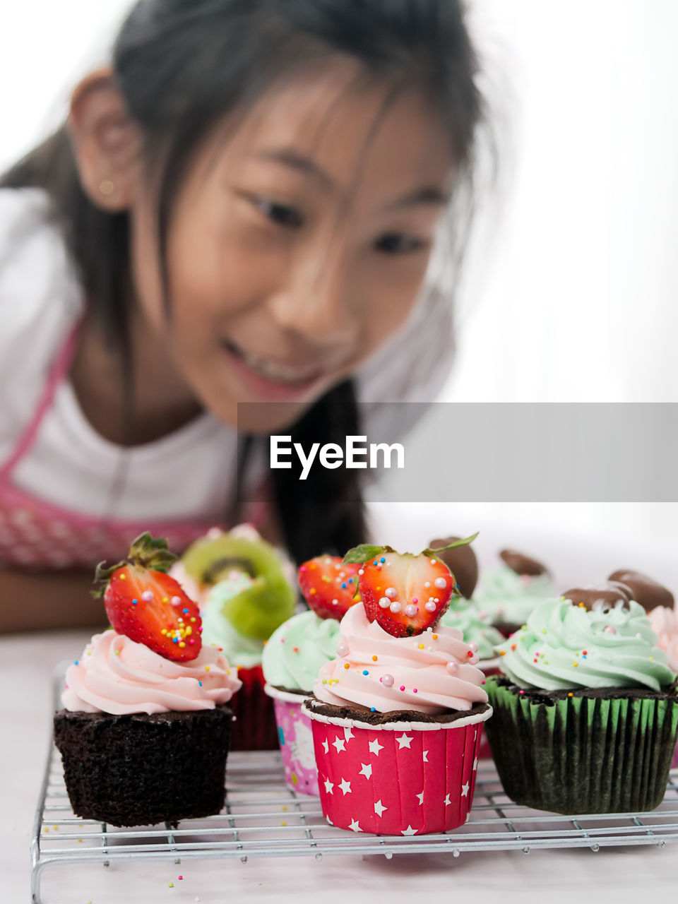 Close-up of girl looking at cupcakes on cooling rack