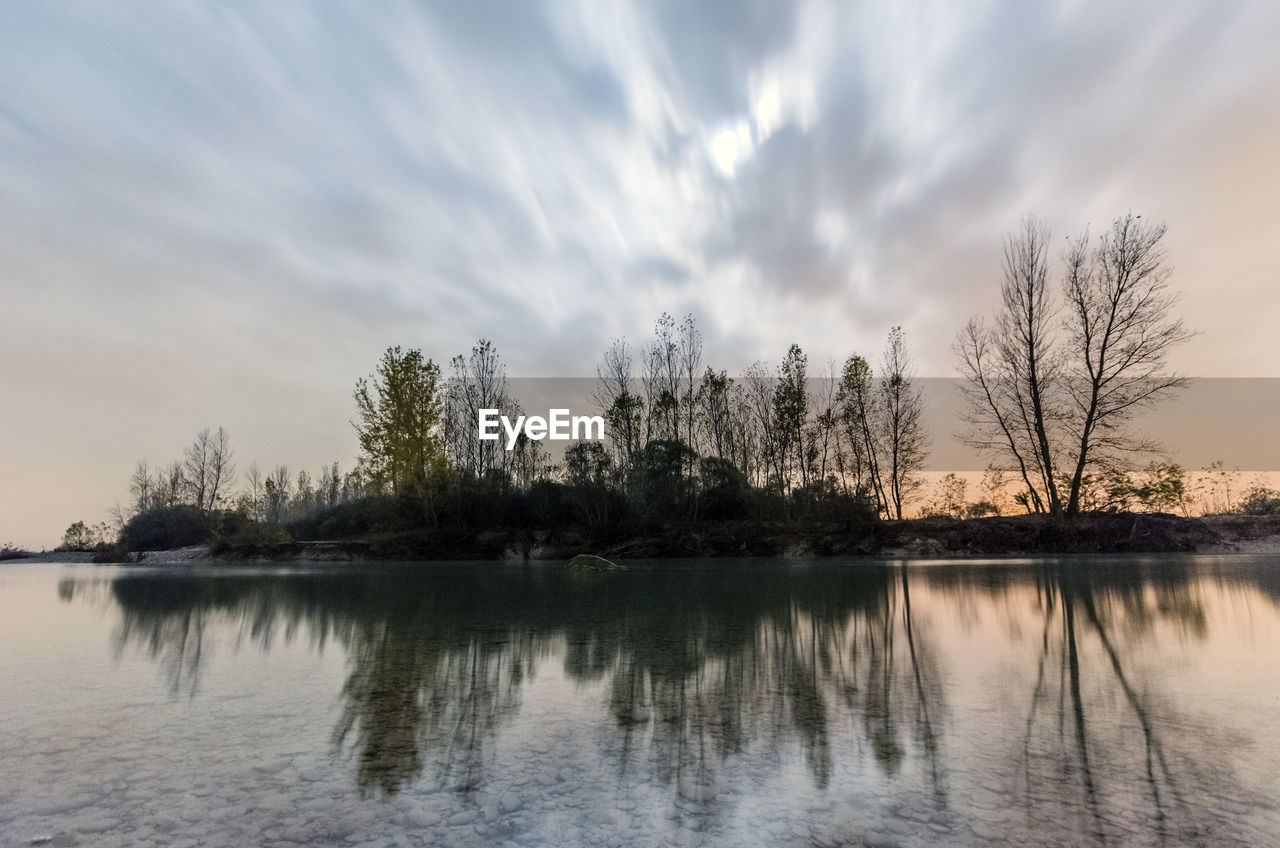 Trees reflecting on calm lake during sunset