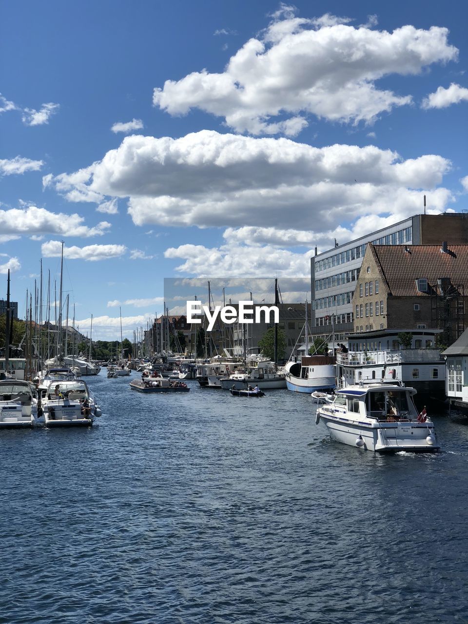 SAILBOATS MOORED ON HARBOR AGAINST BUILDINGS IN CITY