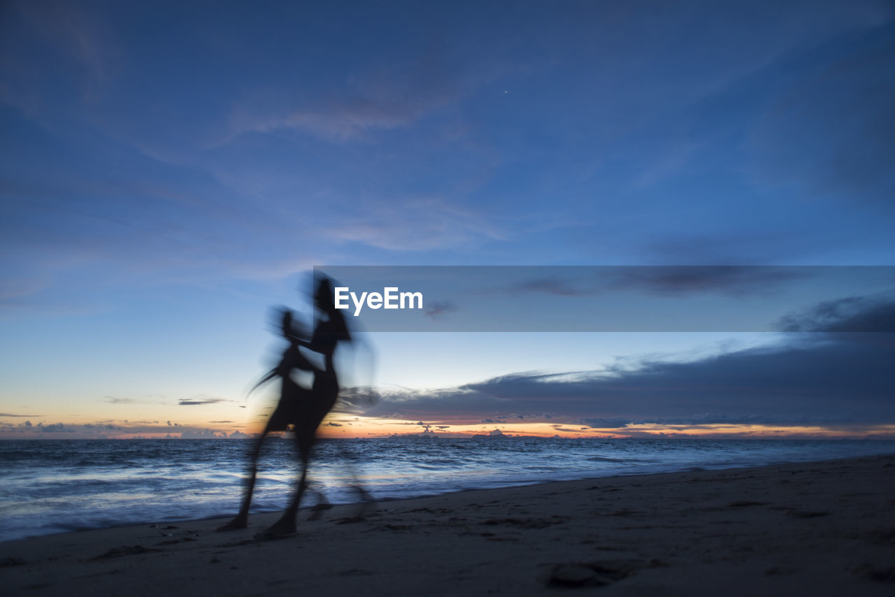 Two women running on a white sand beach at sunset time, koh lanta island, thailand.