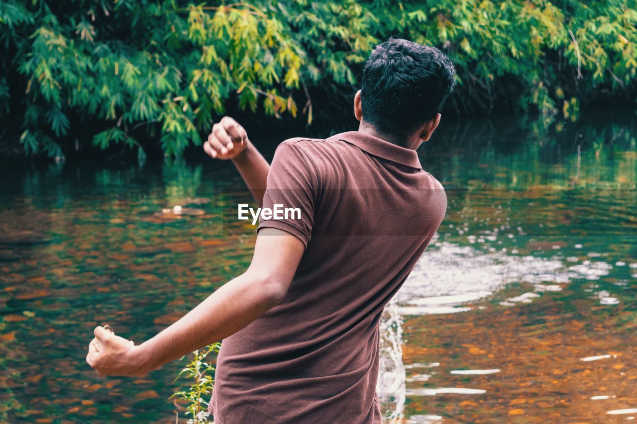 Rear view of man standing by lake