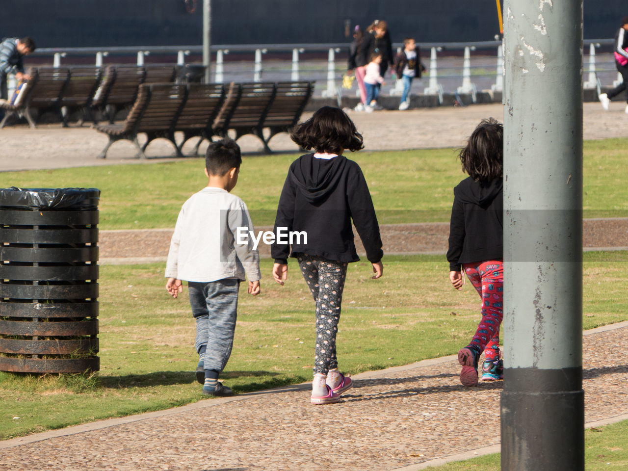 Rear view of children walking on land in park