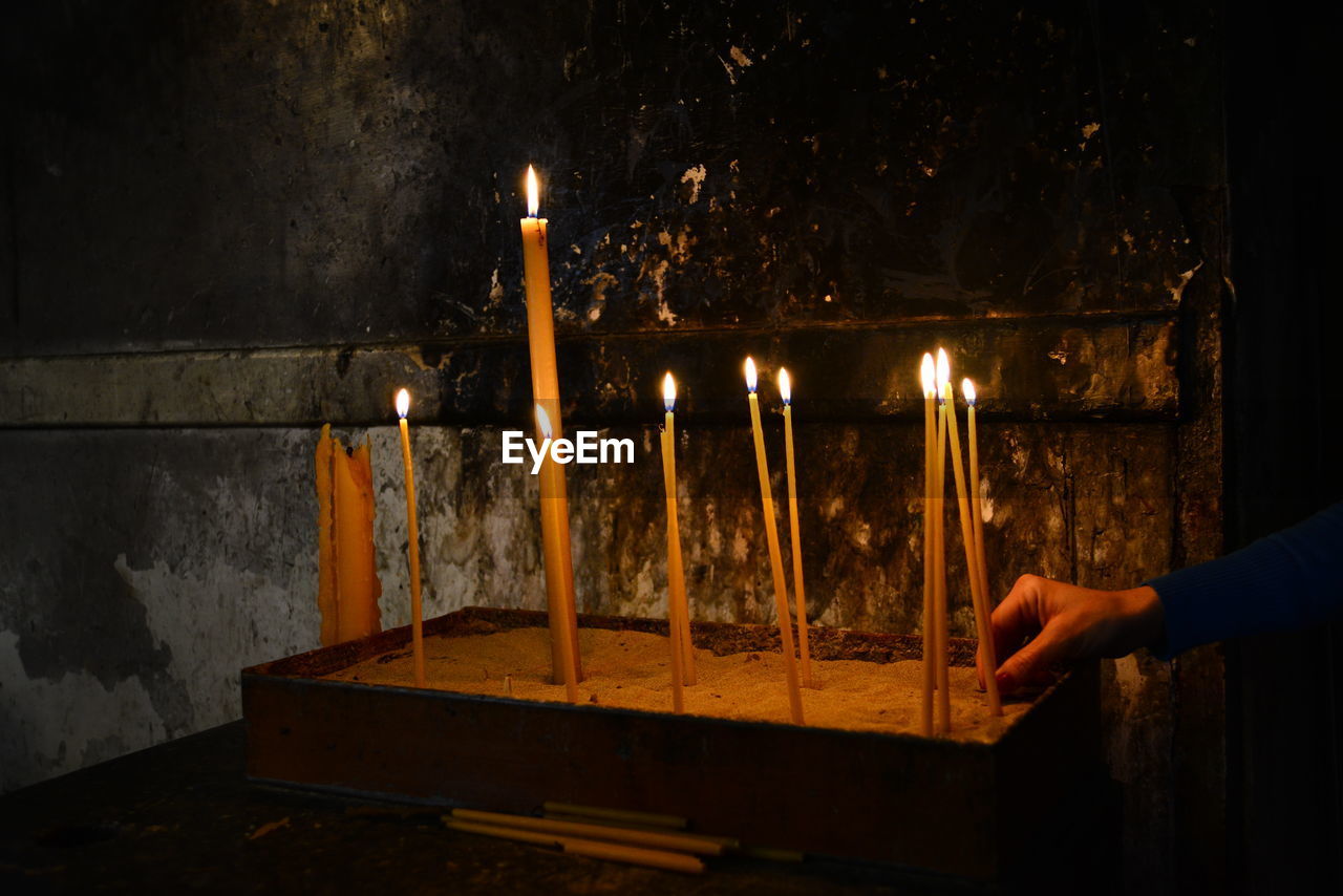 Close-up of hand holding lit candles in temple