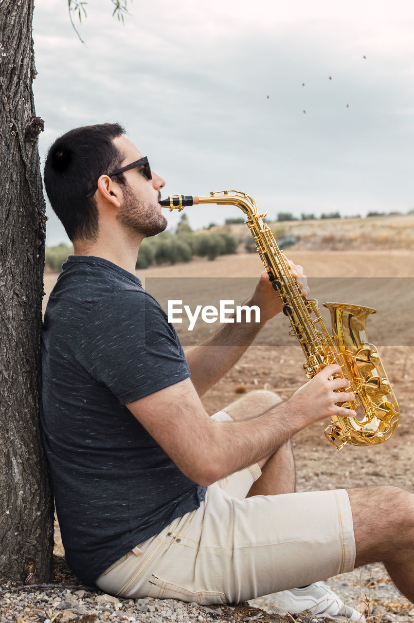 Man holding saxophone while outdoors