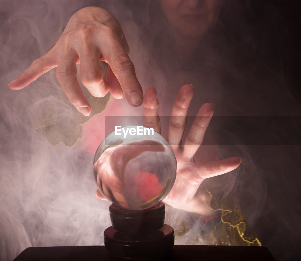 A fortune teller's hands conjure up a crystal ball.