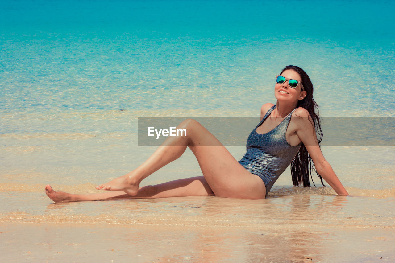 Full length woman wearing swimwear while lying at beach