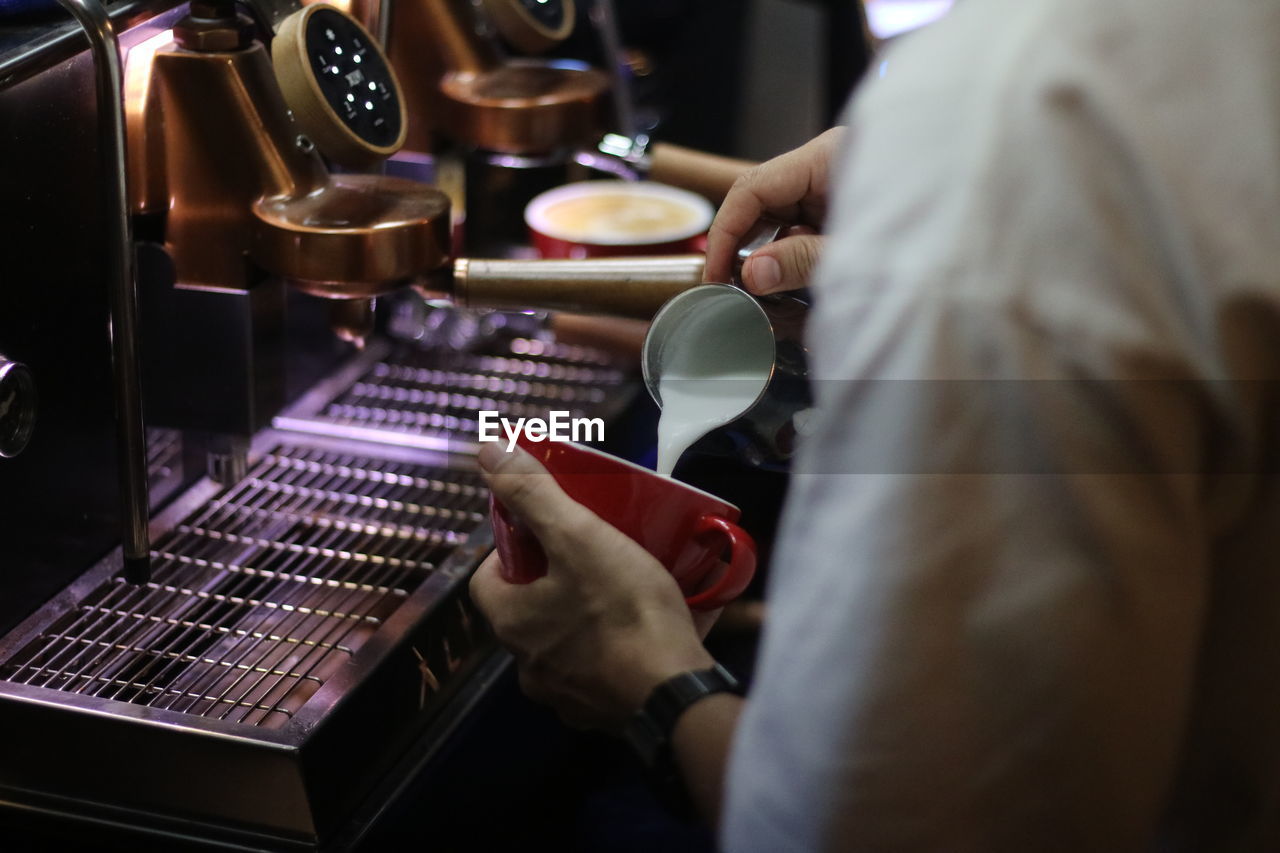 The barista pouring milk make coffee