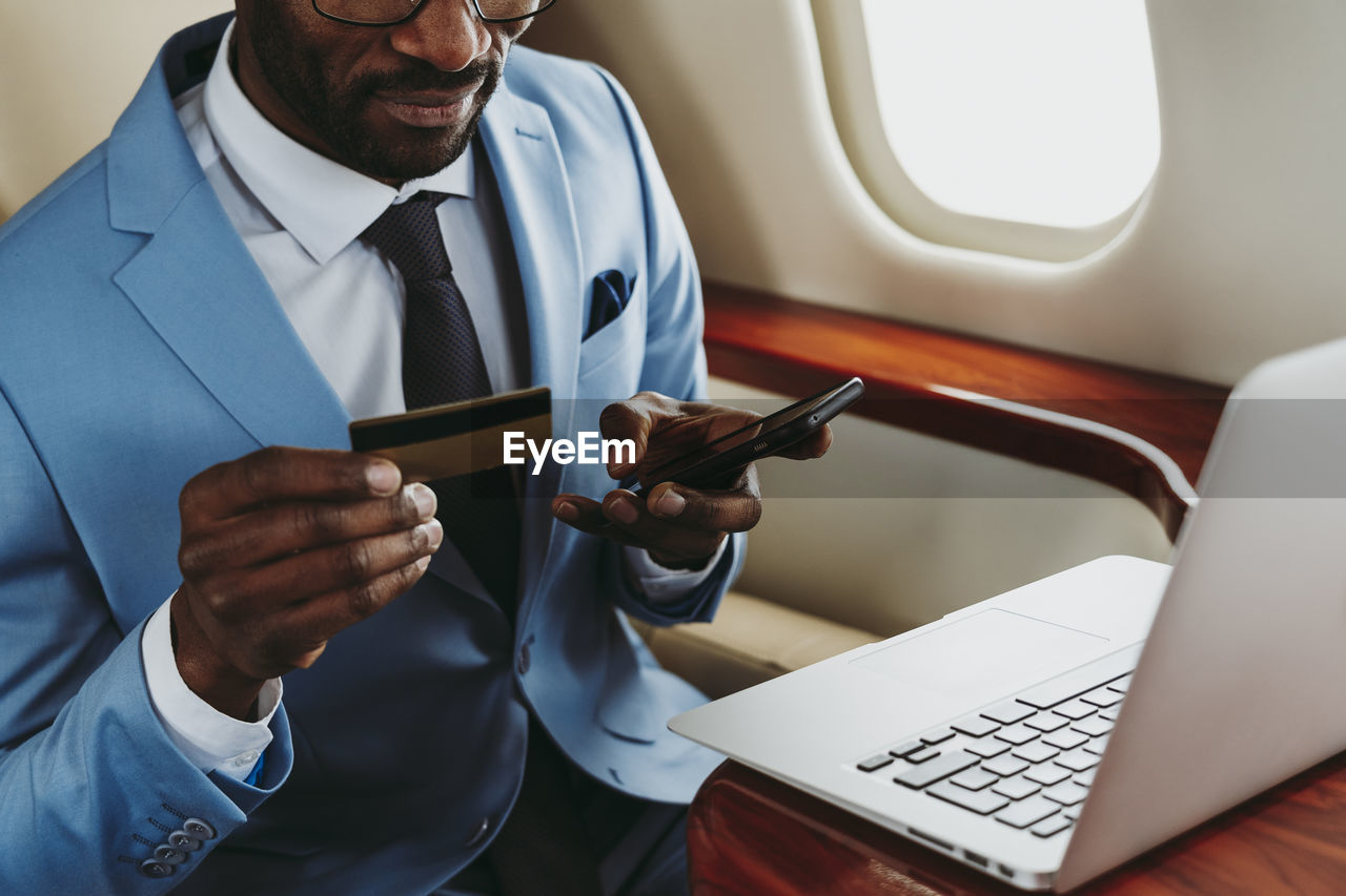 Male entrepreneur paying online through smart phone in private jet