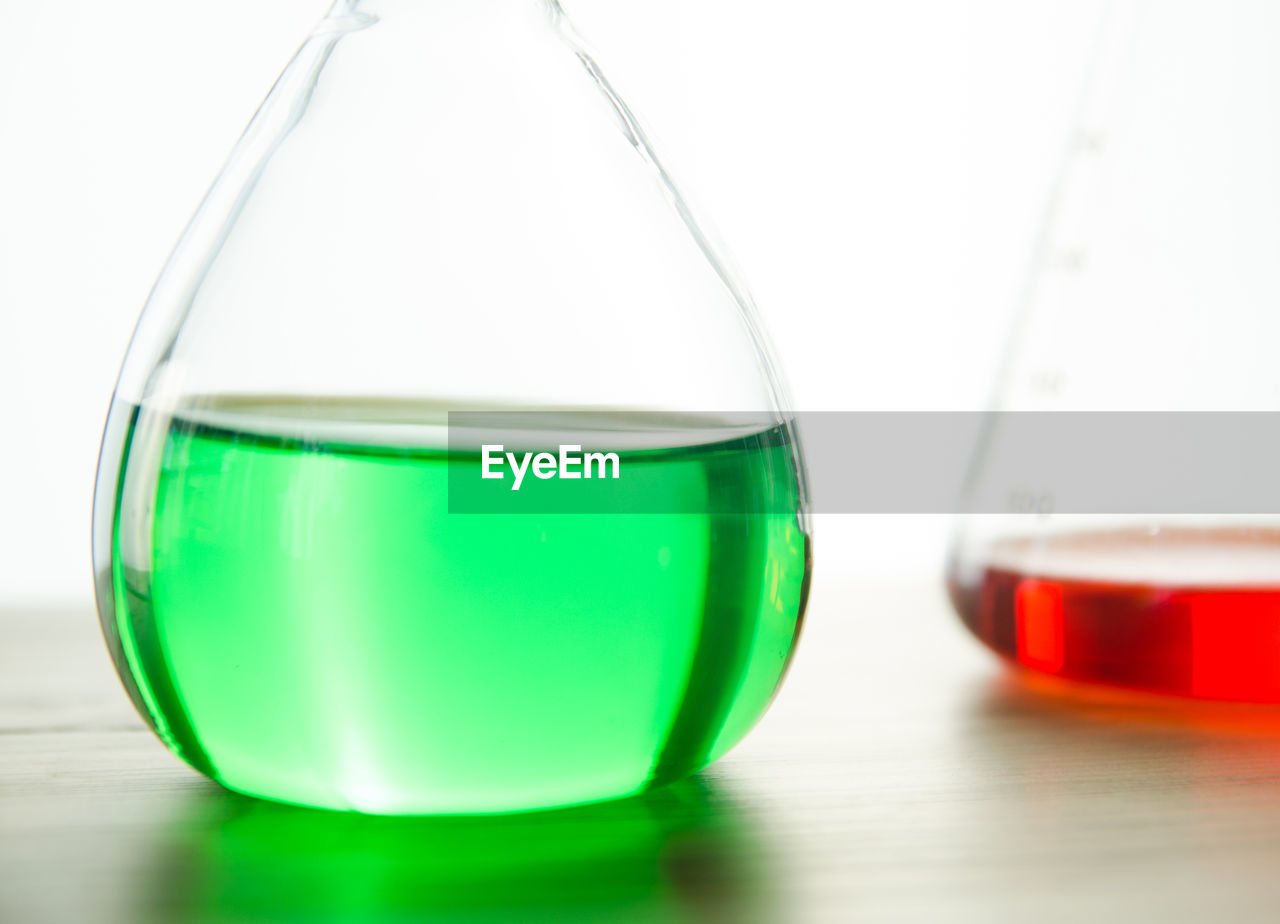 Colorful chemicals in laboratory glassware on table against white background