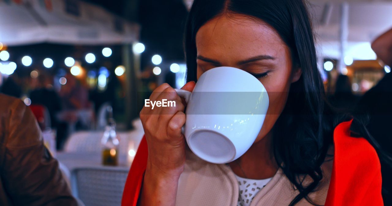 MIDSECTION OF WOMAN DRINKING COFFEE WITH CUP