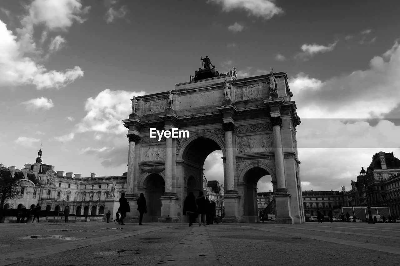 People at arc de triomphe du carrousel against sky