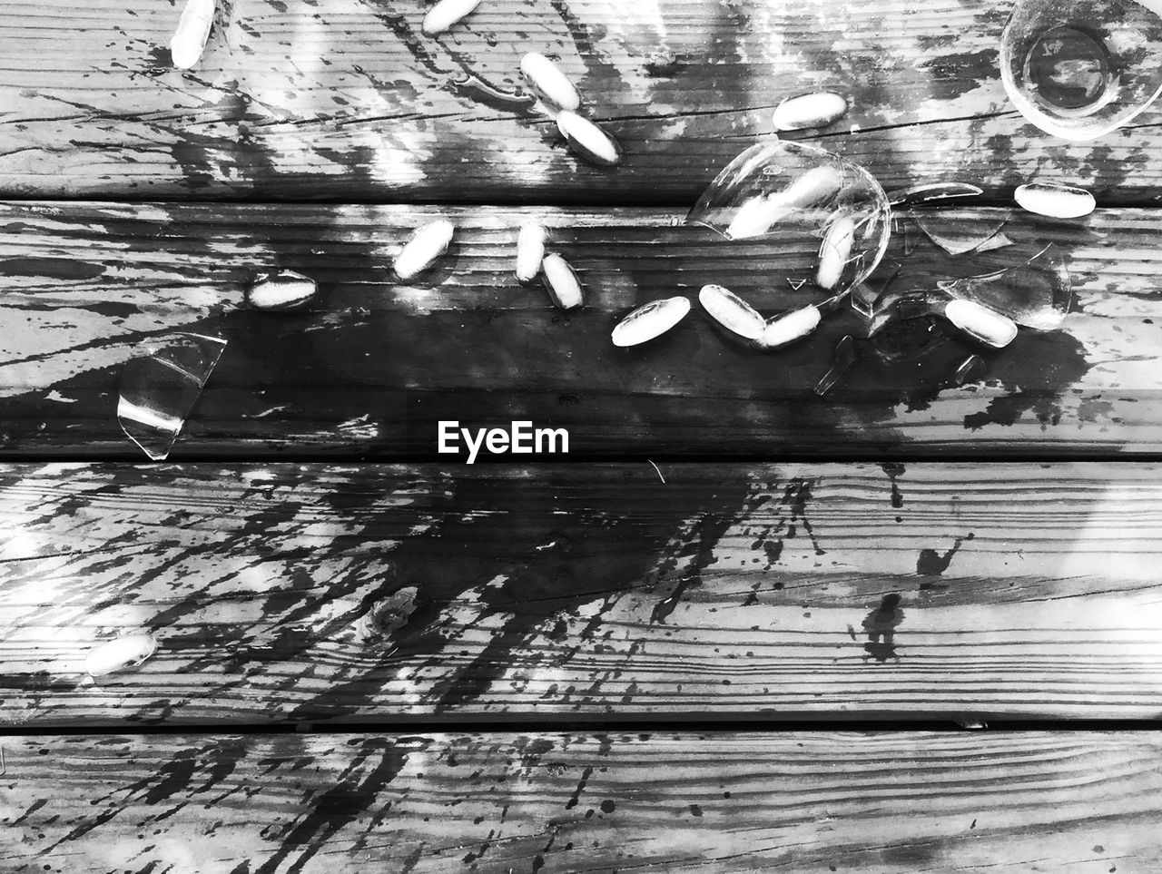 High angle view of broken drinking glass on wooden flooring